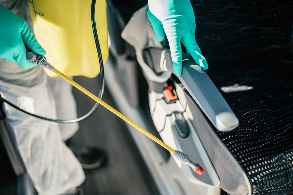 Professional chemical cleaning of bus seats. Bus disinfection. Exterminator in workwear.